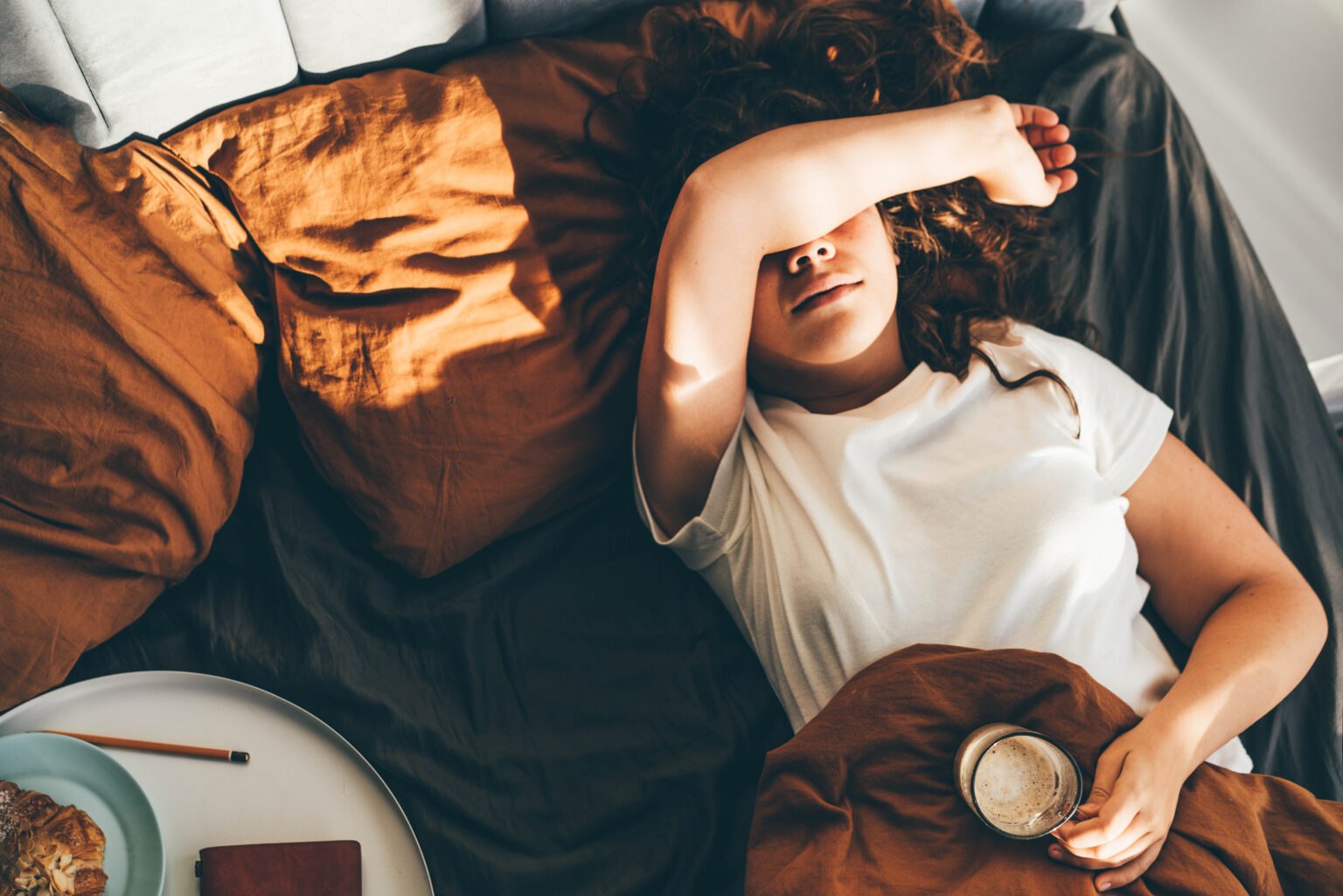 Top view of woman laying on bed in bad mood. Unhappy female at home alone.