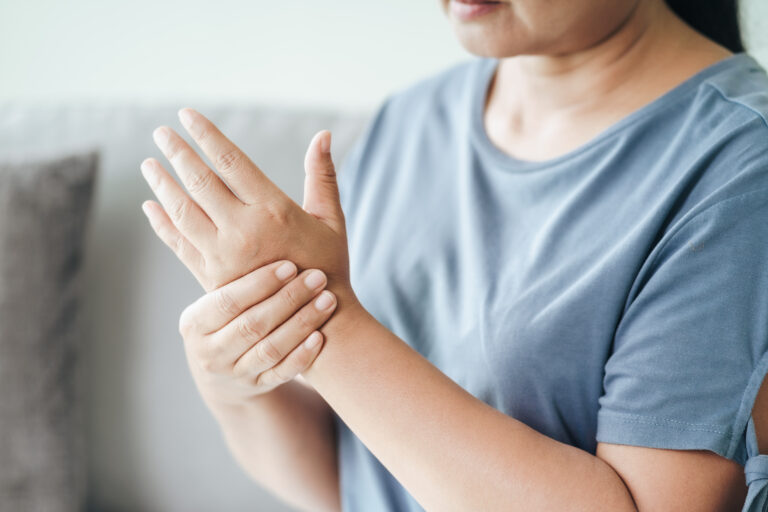 Closeup of woman sitting on sofa holds her wrist. hand injury, feeling pain. Health care and medical concept.