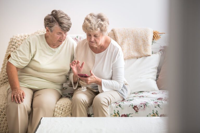 Two senior woman learning together how to use a mobile phone