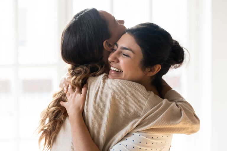 Candid multiracial girls best friends embracing standing indoors